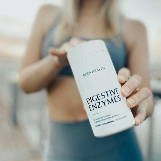 Person holding a supplement bottle labeled 'Digestive Enzymes' by 'Body Health'.