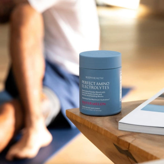 Blue container of Perfect Amino Electrolytes on a wooden table with a blurred background